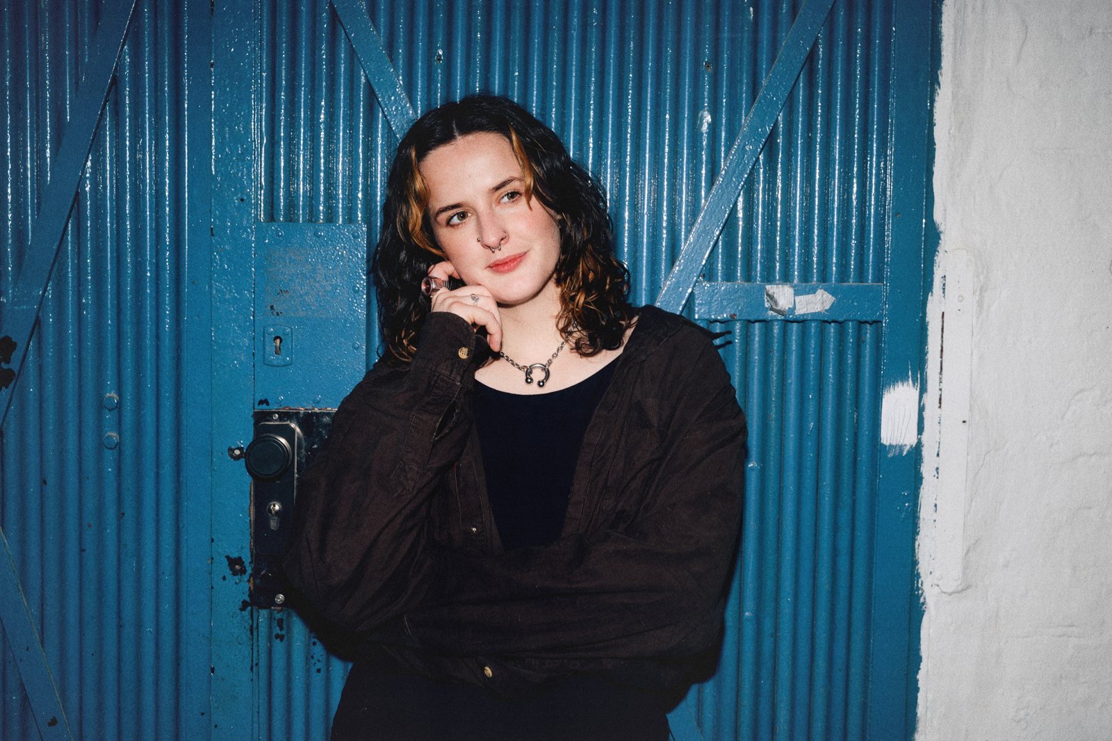 Eva Short against a blue corrugated door